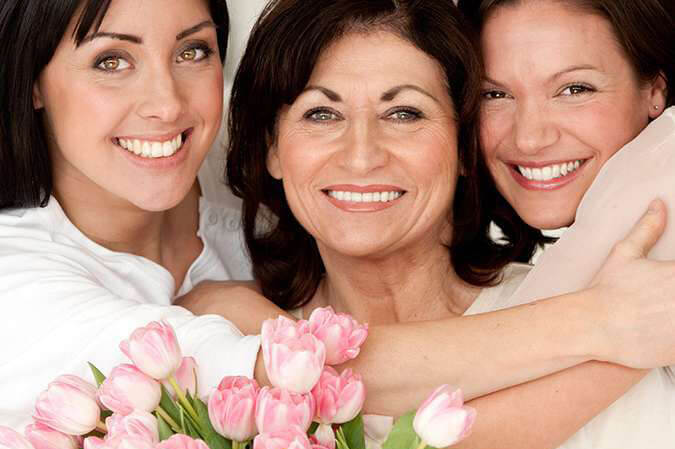 Mega Semana das Mães na Mega-Sena Mães com suas 2 filhas, recebendo flores